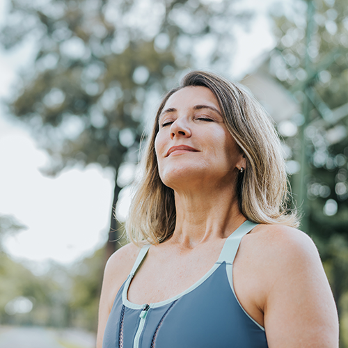 Femme en tenue de sport qui fait une pause dans un parc pour ressentir le bien-être